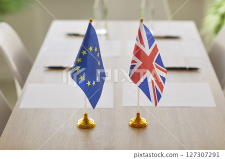 Negotiations between European Union and Great Britain in boardroom with flags on table. Negotiations between European Union and Great Britain in boardroom with flags on table. 127307291