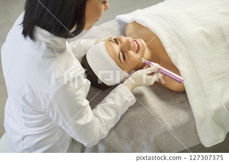 Cosmetologist, dermatologist beautician using dermapen miconeedling roller pen performing face care 127307375