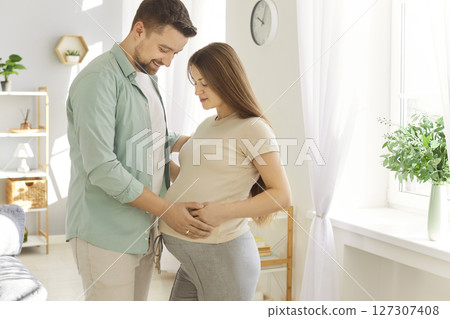 Loving couple standing belly hug, future parents expecting first baby close at home, caring Loving couple standing belly hug, future parents expecting first baby close at home, caring 127307408