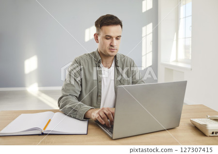 Confident business man looking seriously at computer monitor screen working in office. 127307415