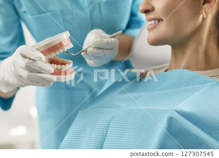 Stomatology doctor showing jaw model to explain dental diseases and treatments, whitening procedure Stomatology doctor showing jaw model to explain dental diseases and treatments, whitening procedure 127307545