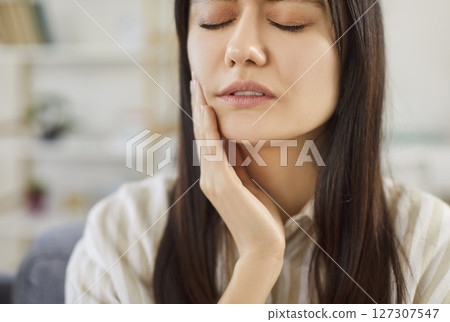 Closeup portrait of a young upset woman suffering from toothache at home. 127307547