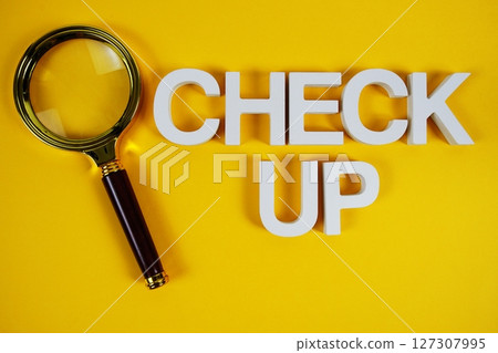 Check up text message and magnifying glass on yellow background 127307995