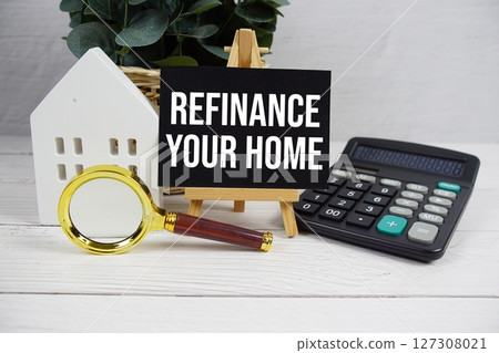 Refinance Your Home on paper card with white house model, calculator and magnifying glass on wooden background 127308021
