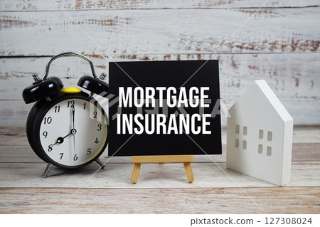 Mortgage Insurance on paper card with white house model, and alarm clock on wooden background Mortgage Insurance on paper card with white house model, and alarm clock on wooden background 127308024