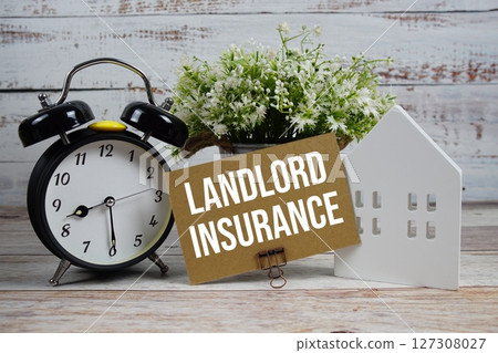 Landlord Insurance on paper card with alarm clock and white house model on wooden background 127308027