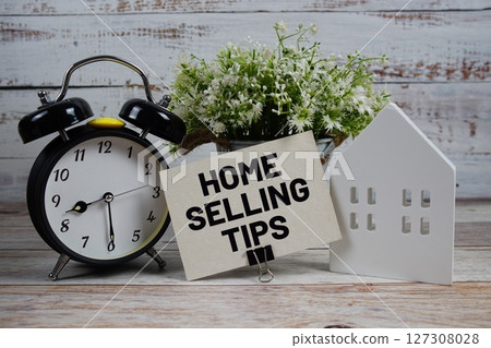 Home Selling Tips on paper card with alarm clock and white house model on wooden background Home Selling Tips on paper card with alarm clock and white house model on wooden background 127308028