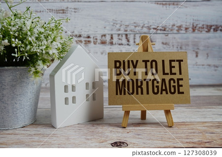 Buy To Let Mortgage on paper card with white house model on wooden background 127308039