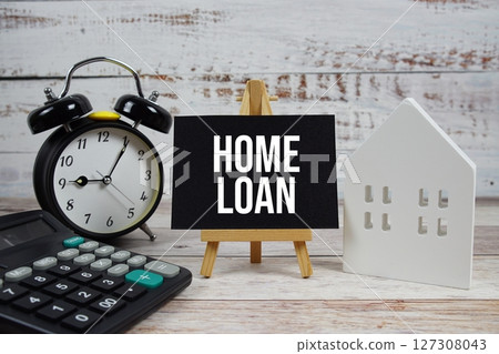 Home Loan on paper card with white house model, calculator and alarm clock on wooden background Home Loan on paper card with white house model, calculator and alarm clock on wooden background 127308043