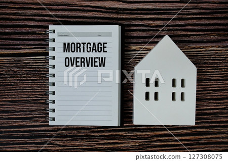 Mortgage Overview on paper notebook with white house model on wooden background Mortgage Overview on paper notebook with white house model on wooden background 127308075