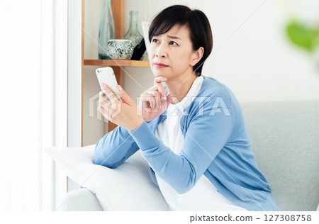 Middle-aged woman making a video call on a smartphone Middle-aged woman making a video call on a smartphone 127308758