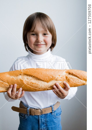 Caucasian child holding baguette with joyful expression Caucasian child holding baguette with joyful expression 127309708