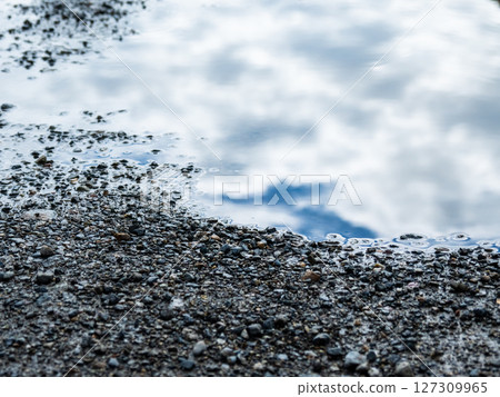 A puddle of gravel reflecting the blue sky and clouds A puddle of gravel reflecting the blue sky and clouds 127309965