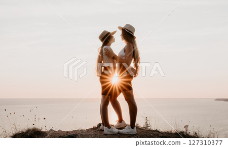 Two Women Embracing at Sunset on a Cliff Two Women Embracing at Sunset on a Cliff 127310377