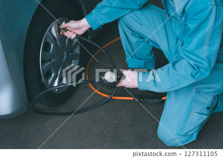 Auto mechanic checking tire pressure 127311105