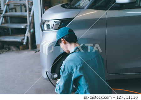 Auto mechanic checking tire pressure Auto mechanic checking tire pressure 127311110
