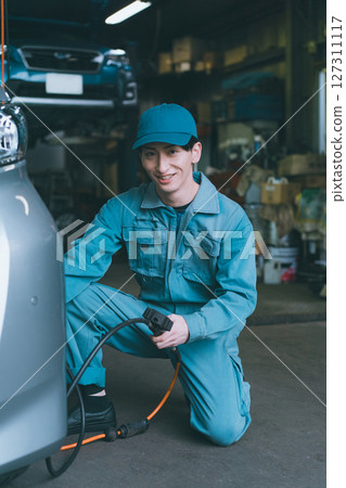 Auto mechanic checking tire pressure 127311117