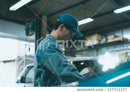 Auto mechanic inspecting engine compartment 127311157