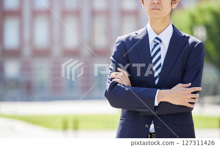 一位身著西裝、雙臂交叉的年輕商人在商業區 127311426