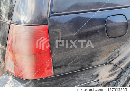 Black car covered in dust during dusty gravel road trip 127313235