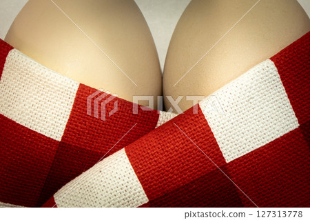 Two eggs are snugly wrapped in a red and white checkered blanket making them look like woman's breast Two eggs are snugly wrapped in a red and white checkered blanket making them look like woman's breast 127313778