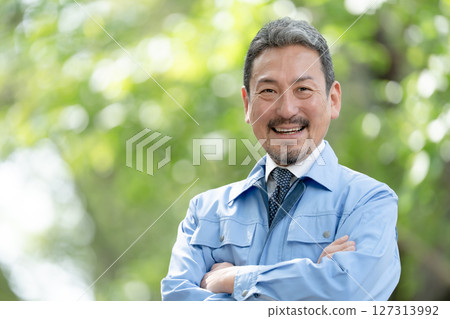 Man in work clothes, fresh green, arms crossed Man in work clothes, fresh green, arms crossed 127313992