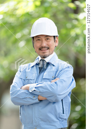 Man in work clothes, fresh green, arms crossed Man in work clothes, fresh green, arms crossed 127314027