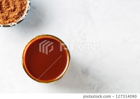 Cocoa Drink in Ridged Glass with Gold Rim and Bowl of Cocoa Powder on Concrete Background, Copy Space Cocoa Drink in Ridged Glass with Gold Rim and Bowl of Cocoa Powder on Concrete Background, Copy Space 127314090