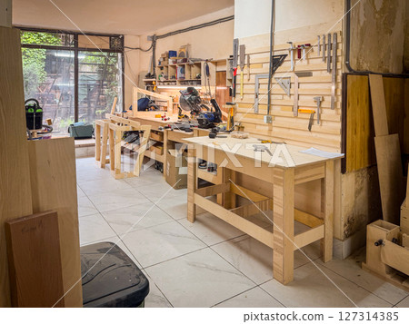 Professional woodworking station with benches, mounted tools, clamps, rulers, and clean surfaces, designed for precision crafting and project planning 127314385