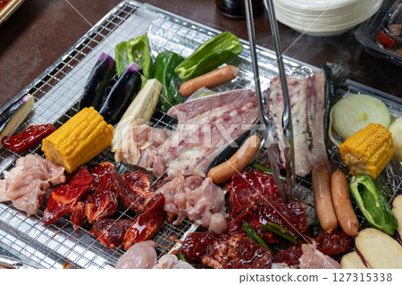 Grilling meat and vegetables on a barbecue 127315338