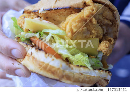 Hand holding a burger, close up photo Hand holding a burger, close up photo 127315451