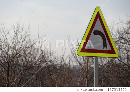 Alert Warning Sign Indicating a Sharp Bend Ahead on a Long and Twisting Rural Road Alert Warning Sign Indicating a Sharp Bend Ahead on a Long and Twisting Rural Road 127315551