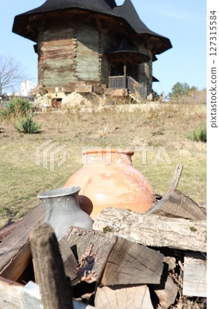 A beautiful rustic landscape showcasing ancient pots alongside a weathered old building 127315584