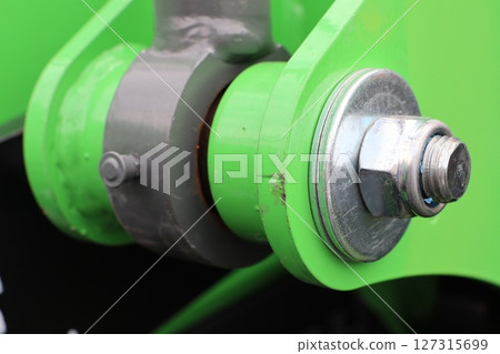 A closeup view of a green mechanical connector prominently featured within machinery components 127315699