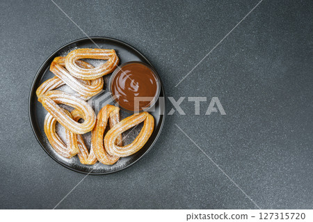 Traditional spanish dessert churros, fried dough pastry and chocolate sause on black background Traditional spanish dessert churros, fried dough pastry and chocolate sause on black background 127315720