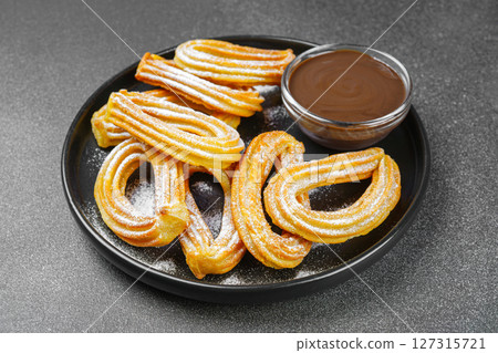 Traditional spanish dessert churros, fried dough pastry and chocolate sause on black background Traditional spanish dessert churros, fried dough pastry and chocolate sause on black background 127315721