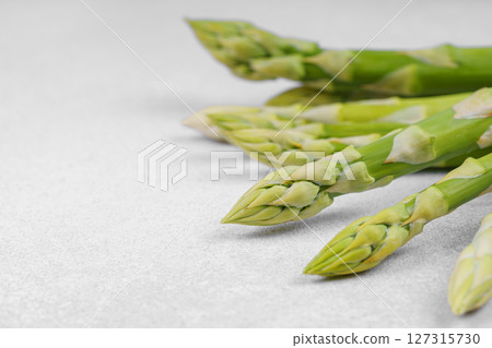Pile of fresh green asparagus or sparrowgrass stems macro, close up on light textured background Pile of fresh green asparagus or sparrowgrass stems macro, close up on light textured background 127315730