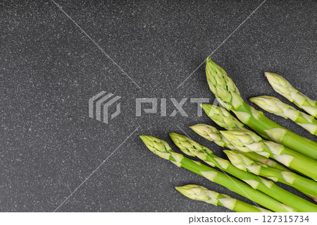 Pile of fresh green asparagus or sparrowgrass stems macro, close up on black textured background Pile of fresh green asparagus or sparrowgrass stems macro, close up on black textured background 127315734