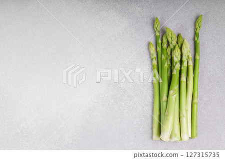 Pile of fresh raw green asparagus or sparrowgrass stems on light textured background with copy space Pile of fresh raw green asparagus or sparrowgrass stems on light textured background with copy space 127315735