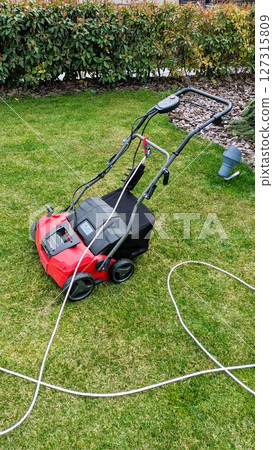 A Lawn Mower on Lush Green Grass Prepared for Detailed Landscaping Work and Maintenance A Lawn Mower on Lush Green Grass Prepared for Detailed Landscaping Work and Maintenance 127315809