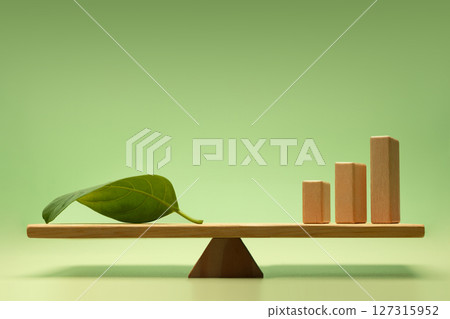 Sustainable, Green investment, financial, and eco-friendly economic growth. Wooden Bar Graph and a Green Leaf balanced on a scale 127315952