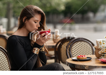 Woman Coffee Cafe: Stylish girl drinking coffee at outdoor cafe in daytime for relaxation. Woman Coffee Cafe: Stylish girl drinking coffee at outdoor cafe in daytime for relaxation. 127317093