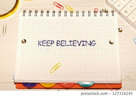 Business concept. Copy space. Concept Words KEEP BELIEVING, a motivational message written on a grid notebook 127318245