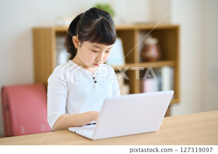 Elementary school girl operating a computer at home Elementary school girl operating a computer at home 127319097