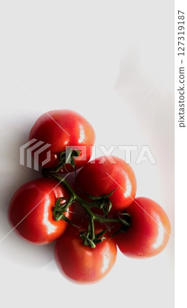 Overhead view of a small bunch of cherry tomatoes still attached to the vine, shot against a clean white background. Overhead view of a small bunch of cherry tomatoes still attached to the vine, shot against a clean white background. 127319187