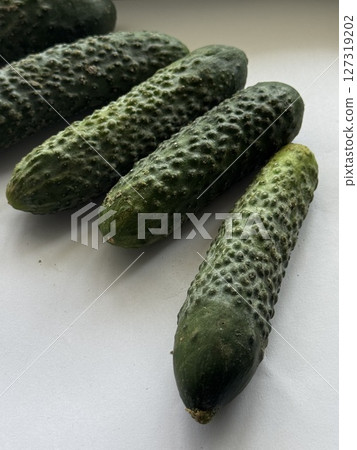 Group of green cucumbers with textured skin arranged on a clean white background, ideal for health and organic food themes. Group of green cucumbers with textured skin arranged on a clean white background, ideal for health and organic food themes. 127319202