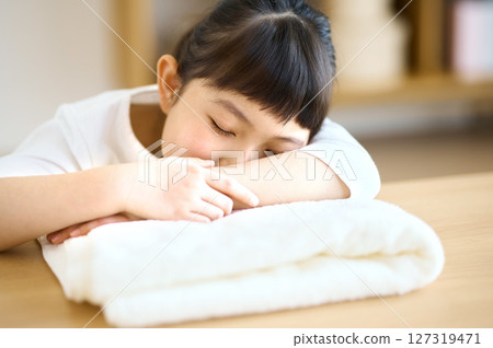 Elementary school girl lying down on a towel and relaxing 127319471
