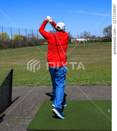 Rear View of a Male Golfer Practicing Swing at Driving Range on a Sunny Day Rear View of a Male Golfer Practicing Swing at Driving Range on a Sunny Day 127319885