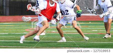 High School Players Engage in Intense Lacrosse Match on a Turf Field 127319953