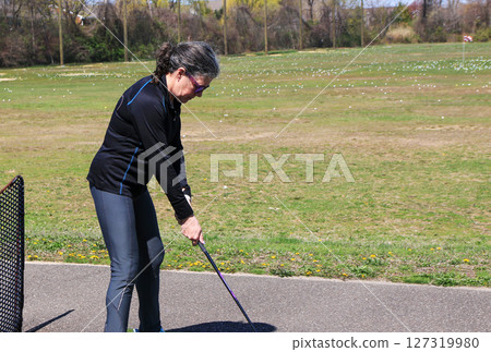 Woman Practicing Golf Swing on Sunny Day at Outdoor Driving Range Woman Practicing Golf Swing on Sunny Day at Outdoor Driving Range 127319980